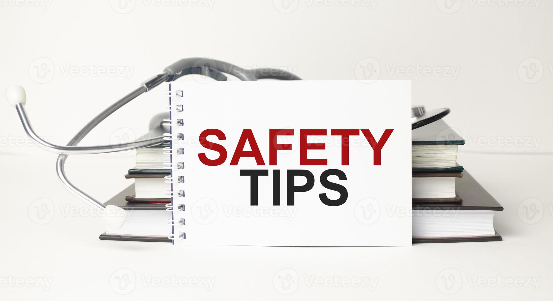 Text safety tips on notebook with stethoscope and pen on wooden background photo