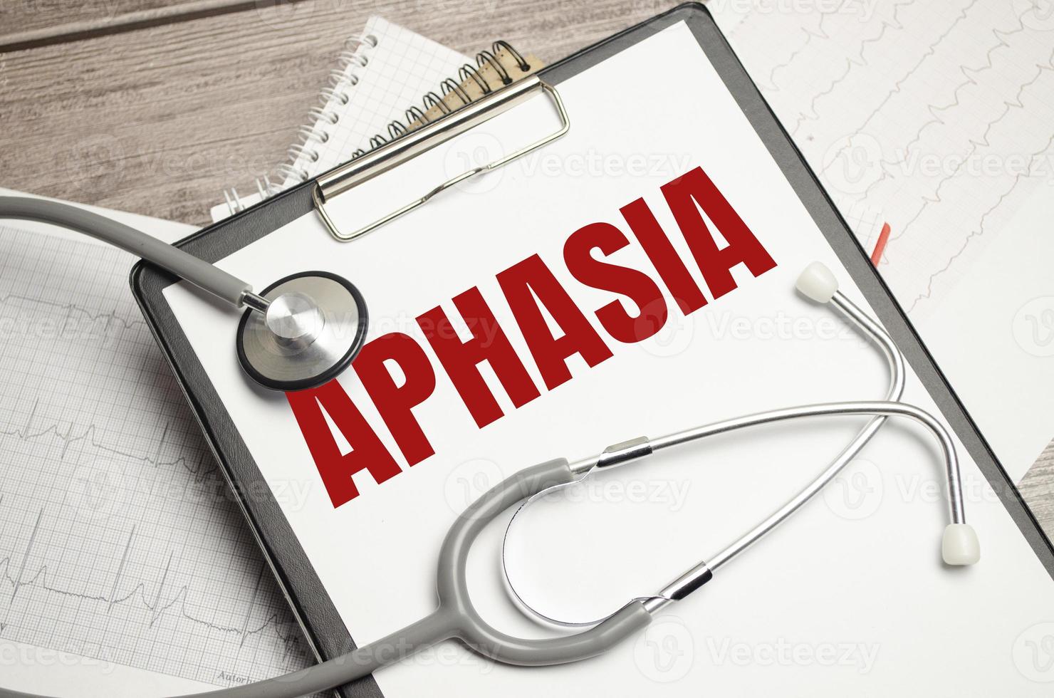 On a brown surface lie pills, a pen, a stethoscope and a notebook with the inscription - aphasia photo