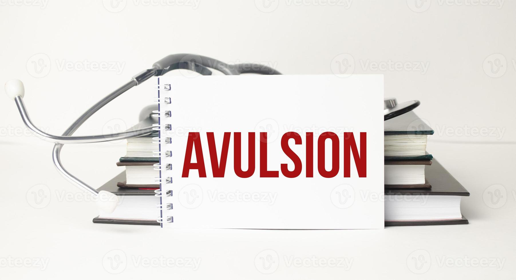 The word avulsion written on a white notepad on a white background near a stethoscope photo