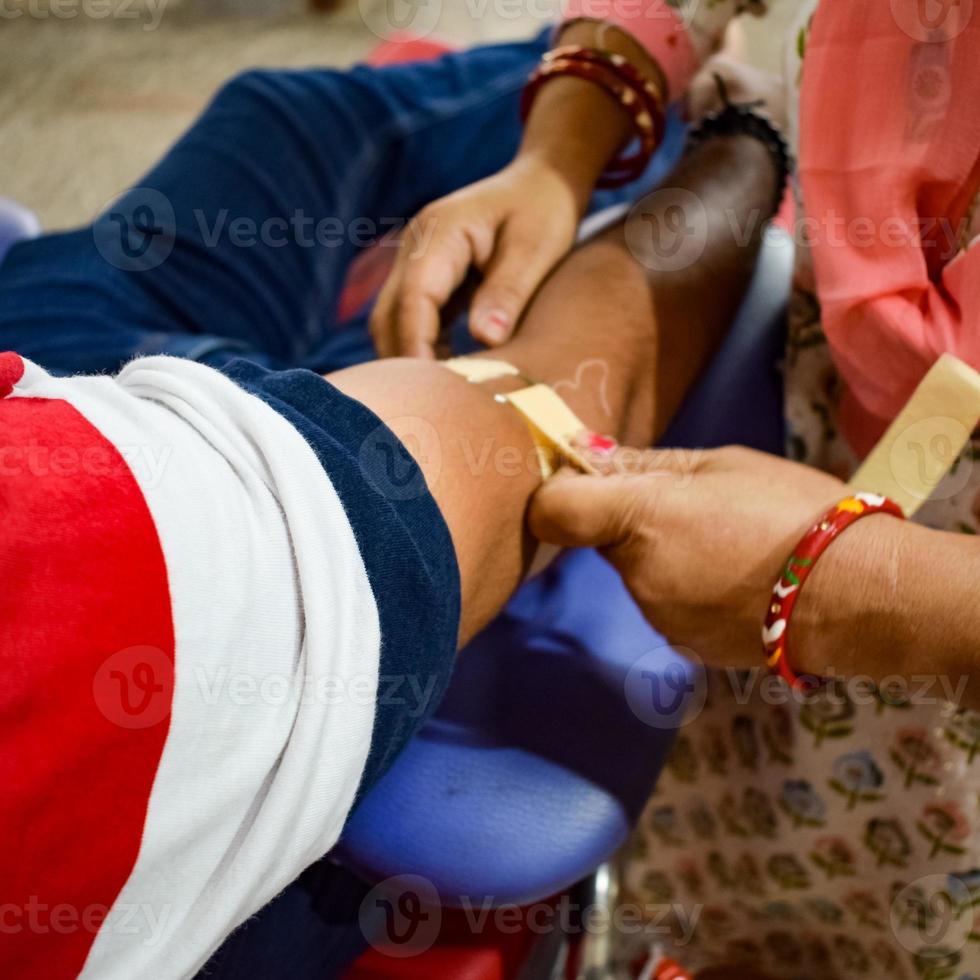 donante de sangre en el campamento de donación de sangre sostenido con una pelota hinchable en la mano en el templo balaji, vivek vihar, delhi, india, imagen para el día mundial del donante de sangre el 14 de junio de cada año, campamento de donación de sangre foto