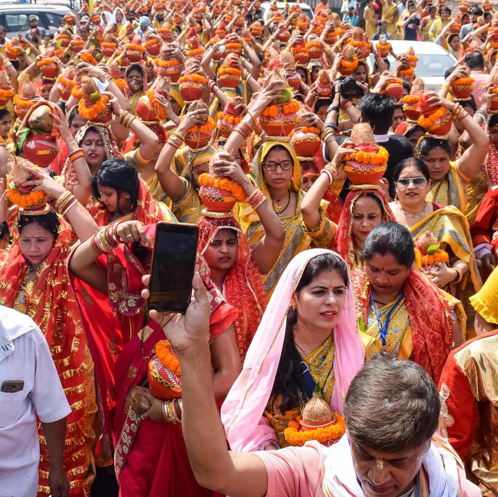 New Delhi, India April 03 2022 - Women with Kalash on head during Jagannath Temple Mangal Kalash Yatra, Indian Hindu devotees carry earthen pots containing sacred water with a coconut on top photo
