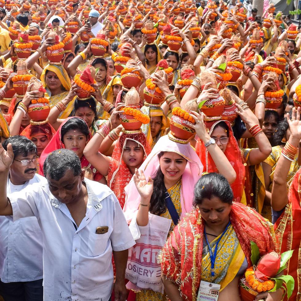 New Delhi, India April 03 2022 - Women with Kalash on head during Jagannath Temple Mangal Kalash Yatra, Indian Hindu devotees carry earthen pots containing sacred water with a coconut on top photo