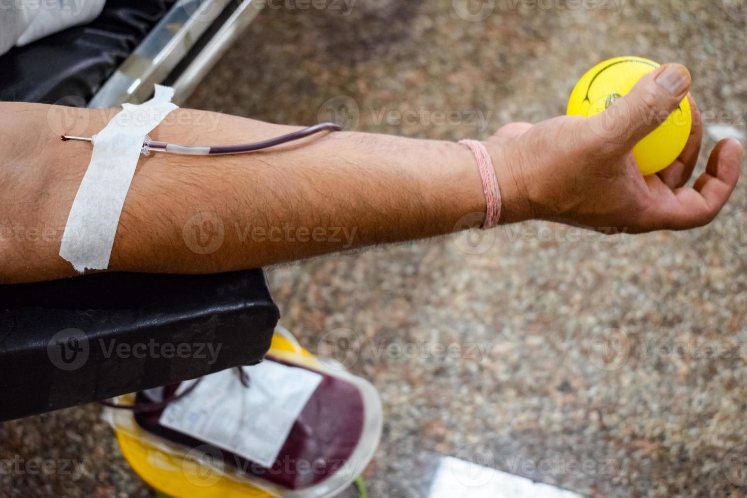 Blood donor at Blood donation camp held with a bouncy ball holding in hand at Balaji Temple, Vivek Vihar, Delhi, India, Image for World blood donor day on June 14 every year, Blood Donation Camp photo