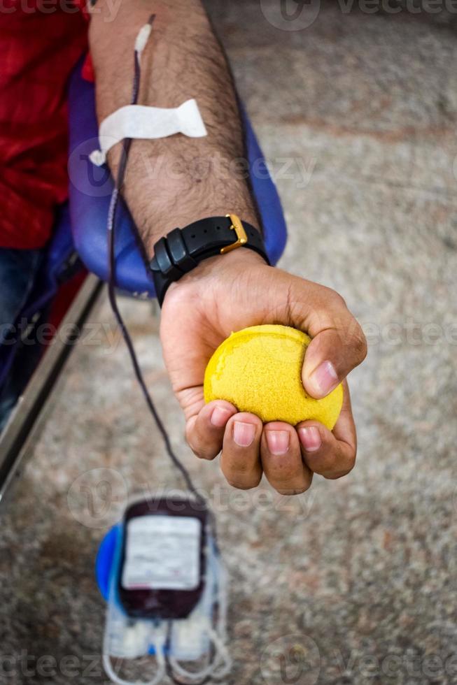 Blood donor at Blood donation camp held with a bouncy ball holding in hand at Balaji Temple, Vivek Vihar, Delhi, India, Image for World blood donor day on June 14 every year, Blood Donation Camp photo