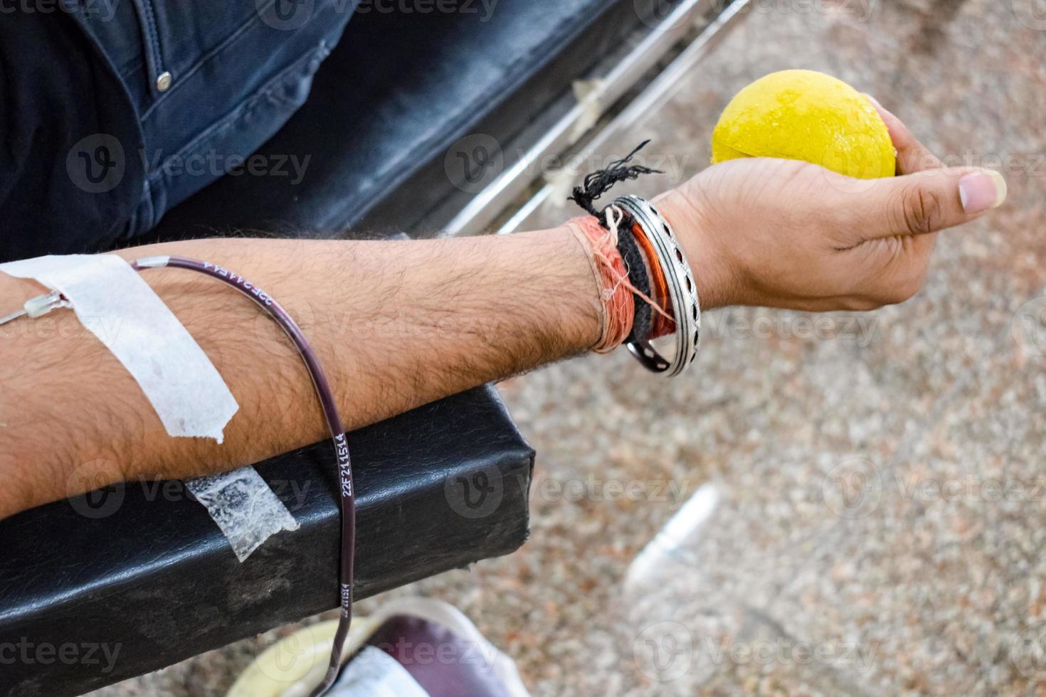 donante de sangre en el campamento de donación de sangre sostenido con una pelota hinchable en la mano en el templo balaji, vivek vihar, delhi, india, imagen para el día mundial del donante de sangre el 14 de junio de cada año, campamento de donación de sangre foto