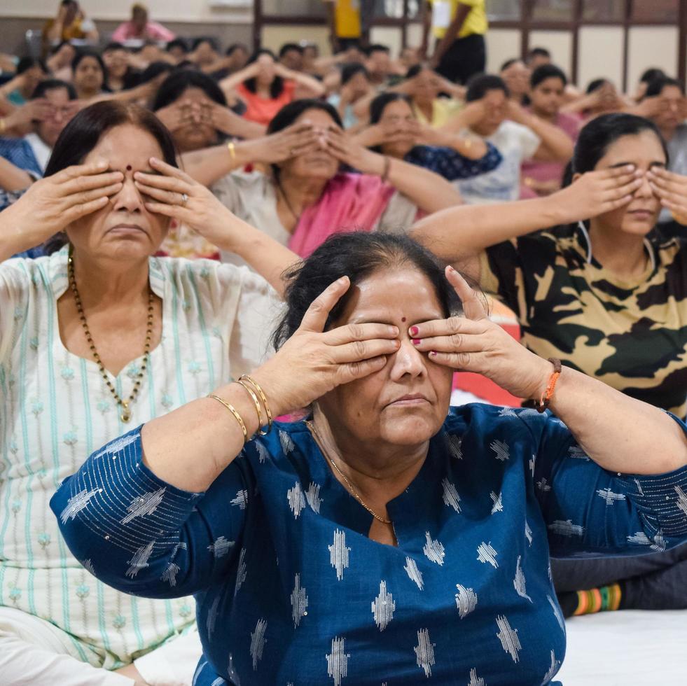 New Delhi, India, June 19 2022 -Group Yoga exercise session for people of different age groups in Balaji Temple, Vivek Vihar, International Yoga Day, Big group of adults attending yoga class in temple photo