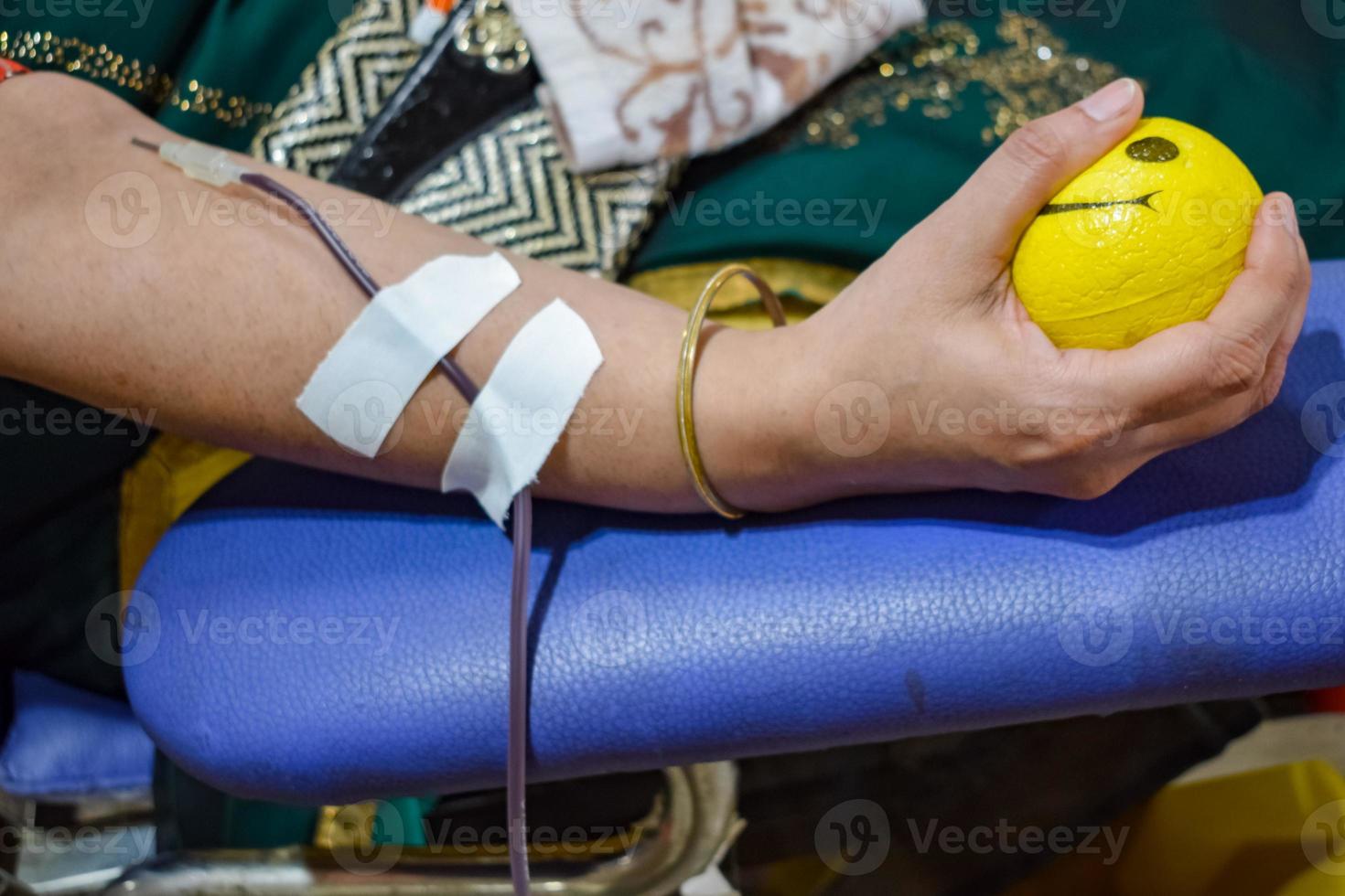 Blood donor at Blood donation camp held with a bouncy ball holding in hand at Balaji Temple, Vivek Vihar, Delhi, India, Image for World blood donor day on June 14 every year, Blood Donation Camp photo