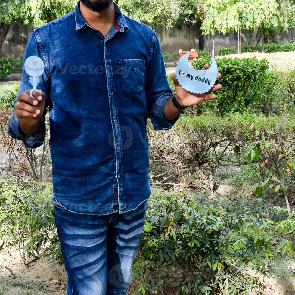 Indian couple posing for maternity baby shoot. The couple is posing in a lawn with green grass and the woman is falunting her baby bump in Lodhi Garden in New Delhi, India photo