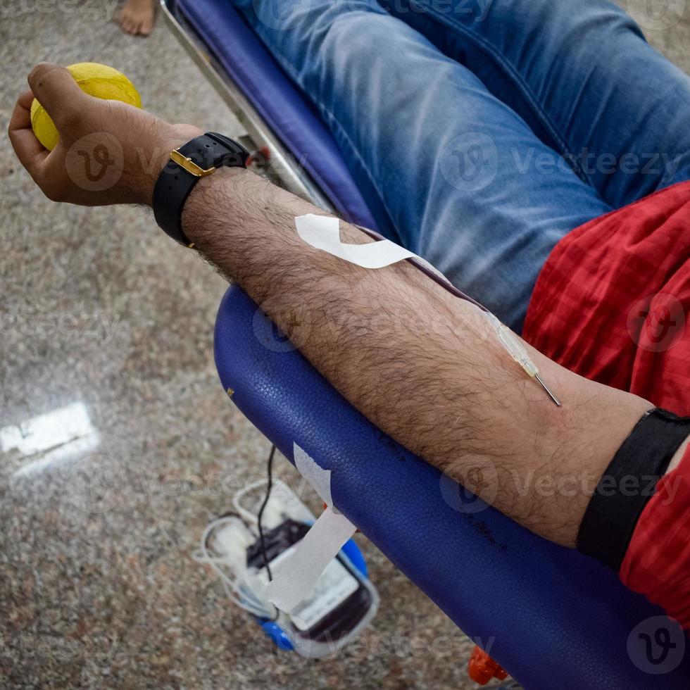 donante de sangre en el campamento de donación de sangre sostenido con una pelota hinchable en la mano en el templo balaji, vivek vihar, delhi, india, imagen para el día mundial del donante de sangre el 14 de junio de cada año, campamento de donación de sangre foto