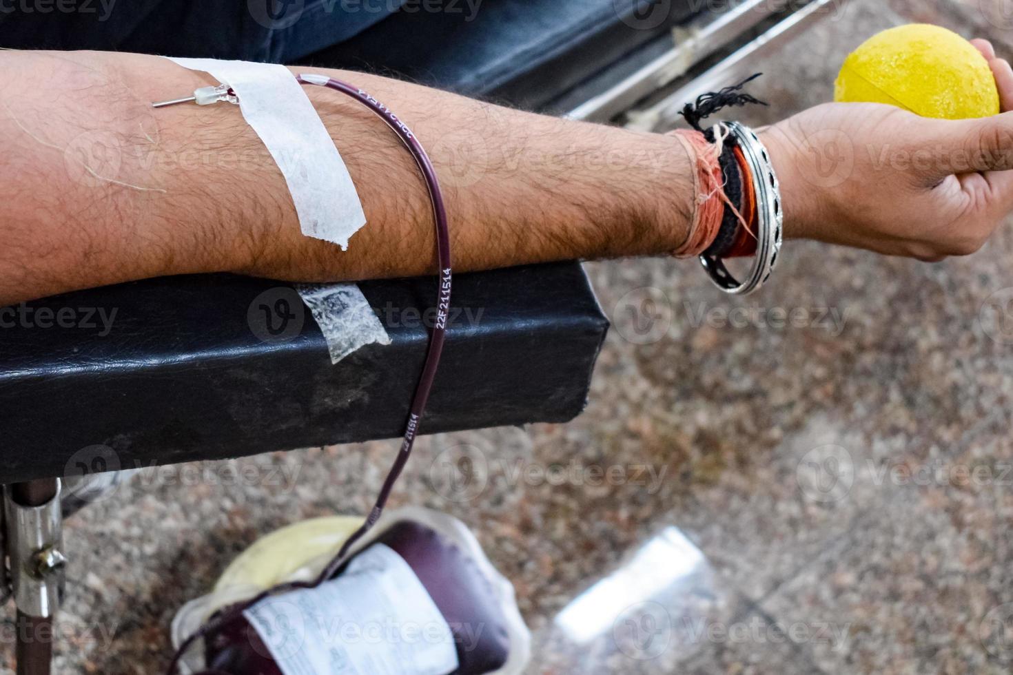 Blood donor at Blood donation camp held with a bouncy ball holding in hand at Balaji Temple, Vivek Vihar, Delhi, India, Image for World blood donor day on June 14 every year, Blood Donation Camp photo