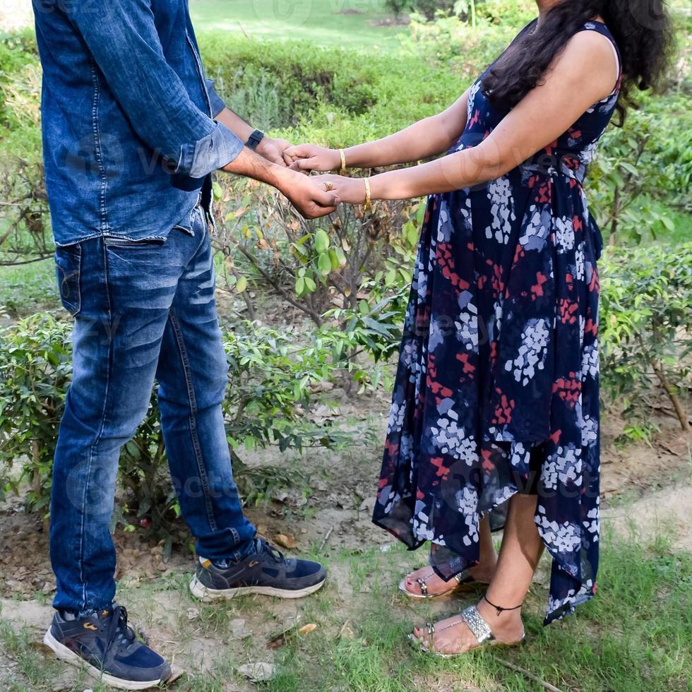 Indian couple posing for maternity baby shoot. The couple is posing in a lawn with green grass and the woman is falunting her baby bump in Lodhi Garden in New Delhi, India photo