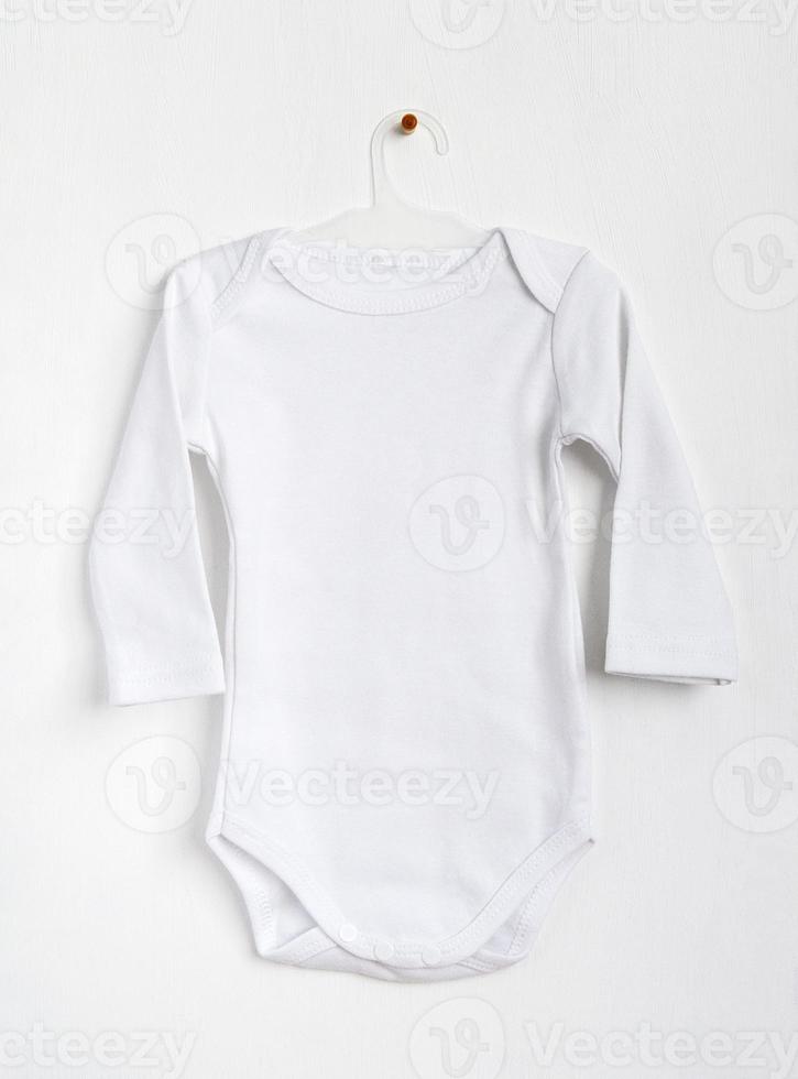 ropa de bebé blanca en una percha. maqueta para diseño foto