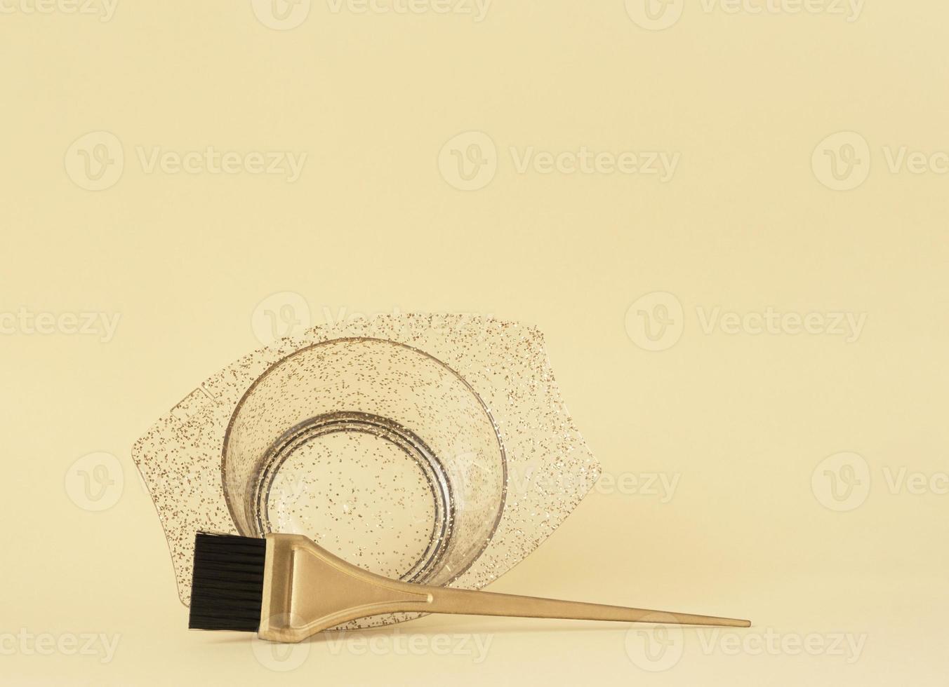 A bowl and a brush for coloring your hair. Gold hair salon accessories on a yellow background with space for text. Banner, template for information. photo