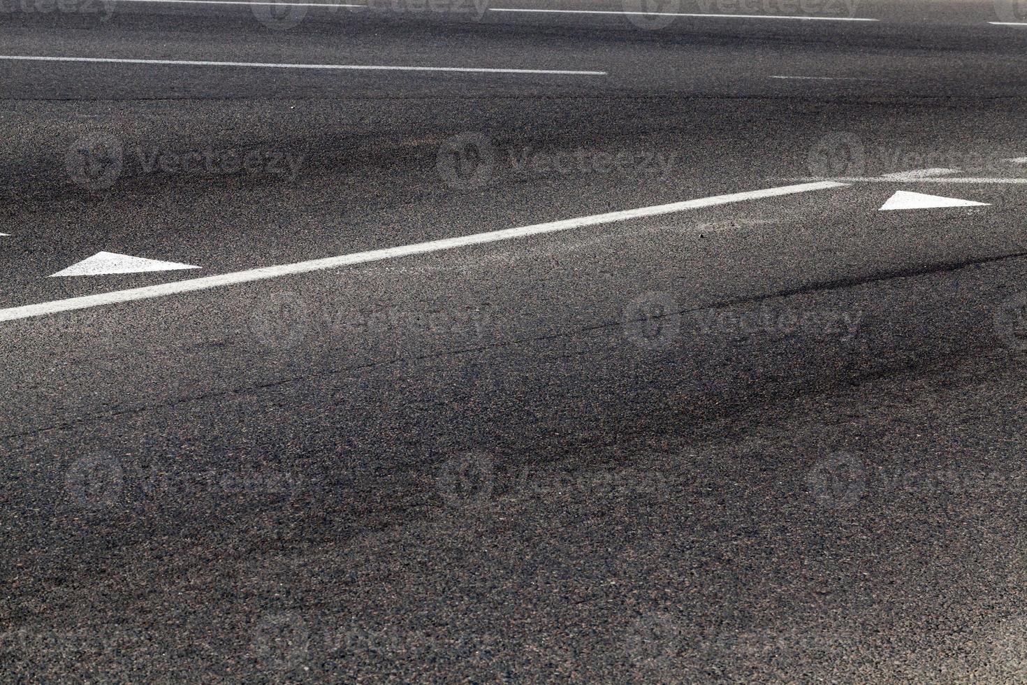 close up of an asphalt road with white road markings photo