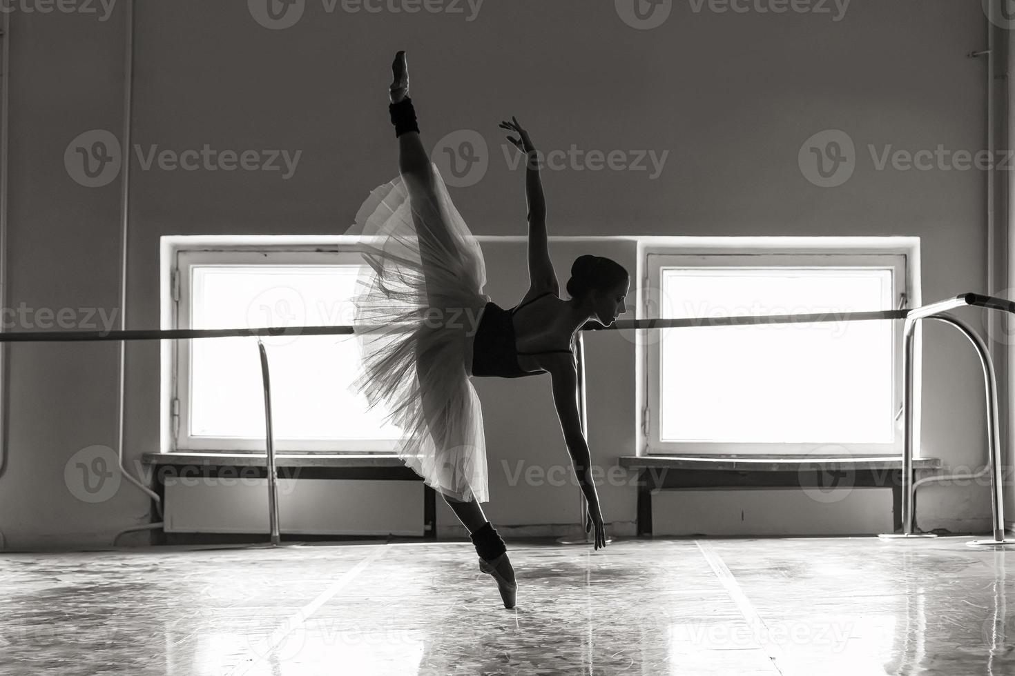 una bailarina encantadora en un traje de cuerpo posa elementos de ballet en un tocado en un estudio fotográfico foto