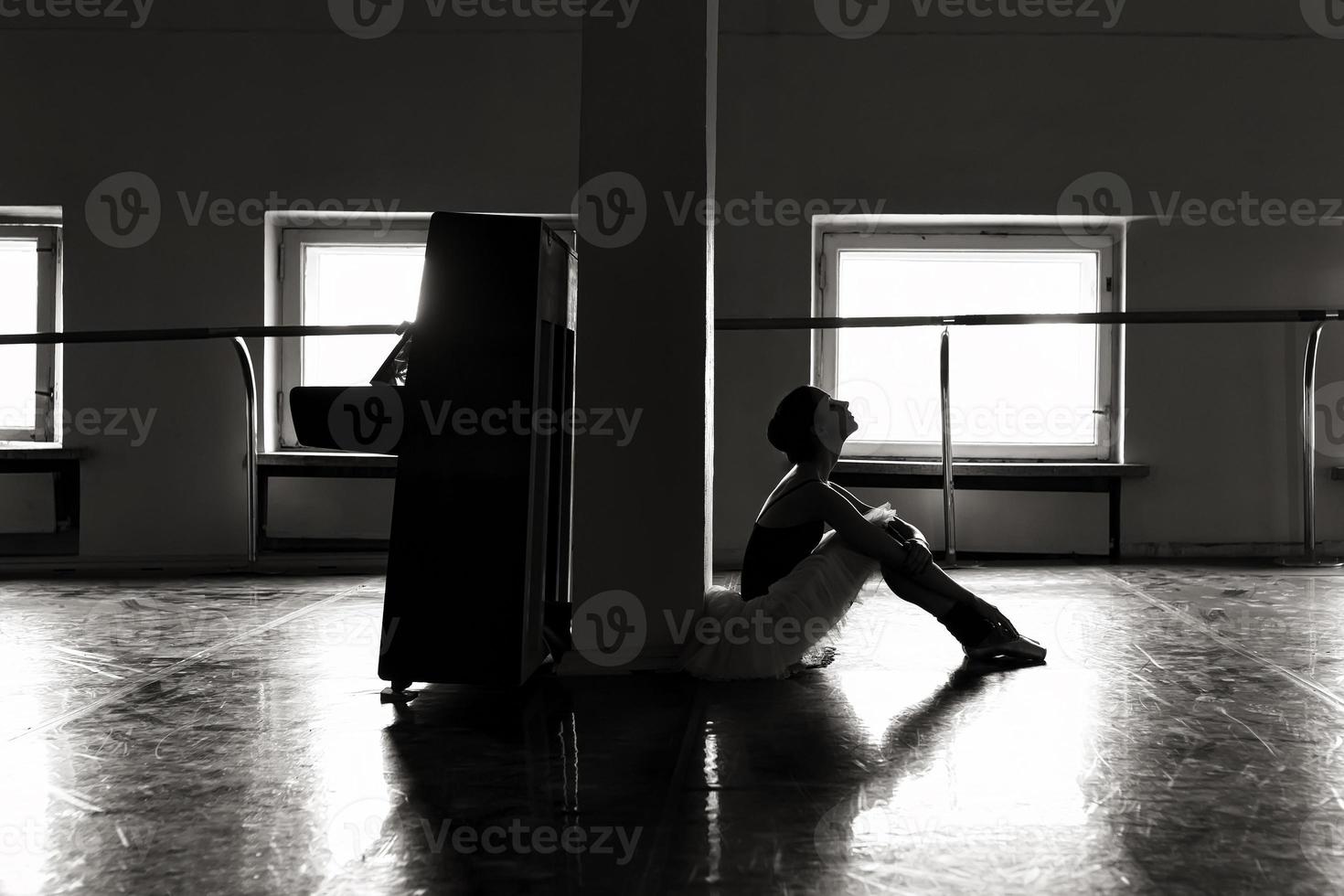 una bailarina encantadora en un traje de cuerpo posa elementos de ballet en un tocado en un estudio fotográfico foto