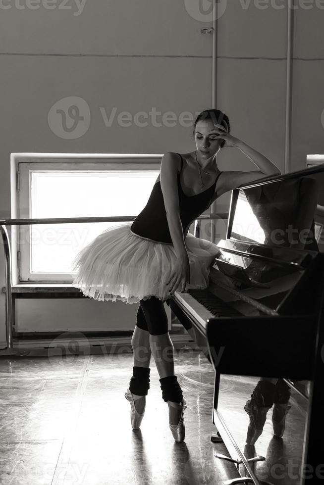 una bailarina encantadora en un traje de cuerpo posa elementos de ballet en un tocado en un estudio fotográfico foto