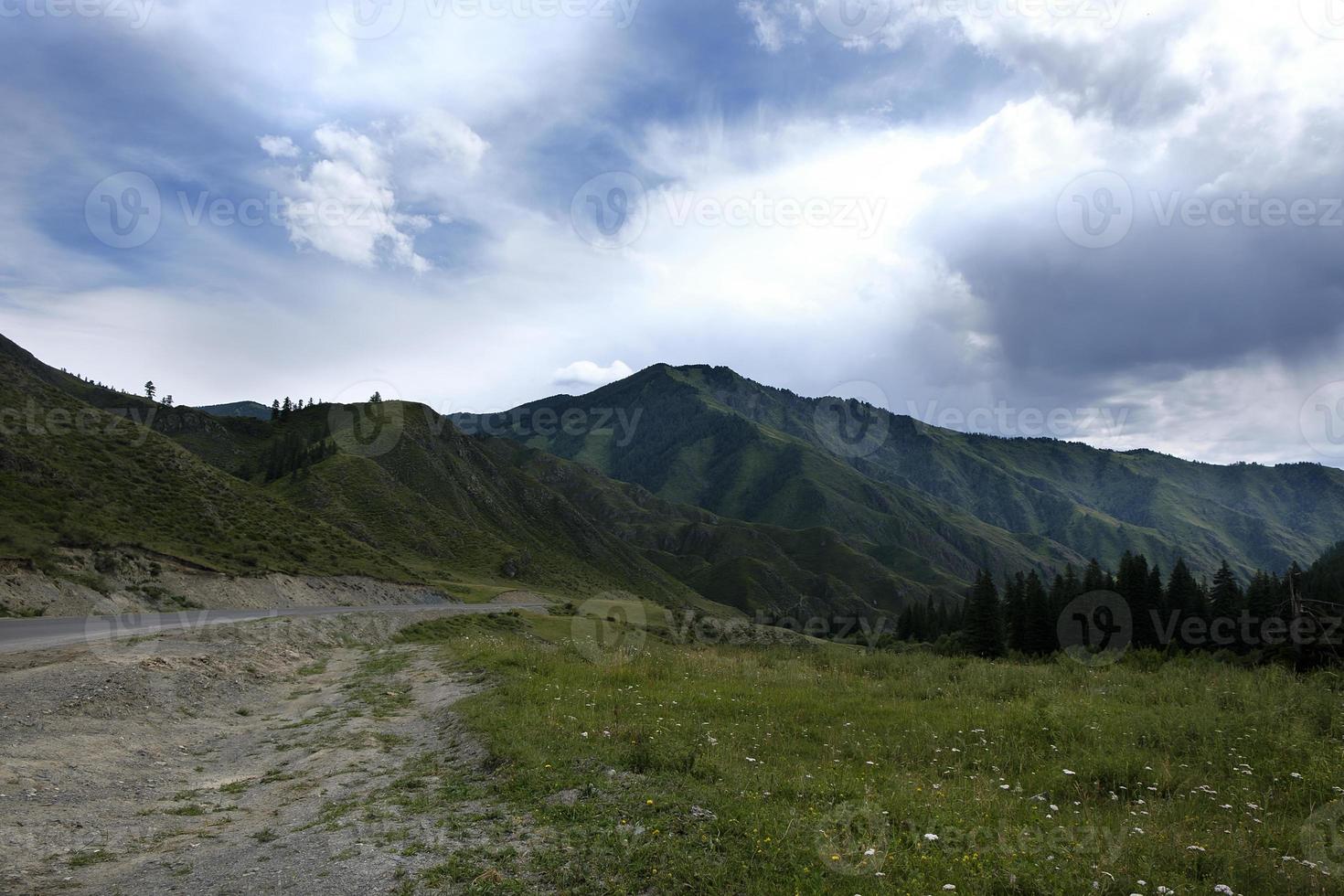 cinta de la carretera entre las laderas de las montañas en las extensiones de altai en un día de verano foto