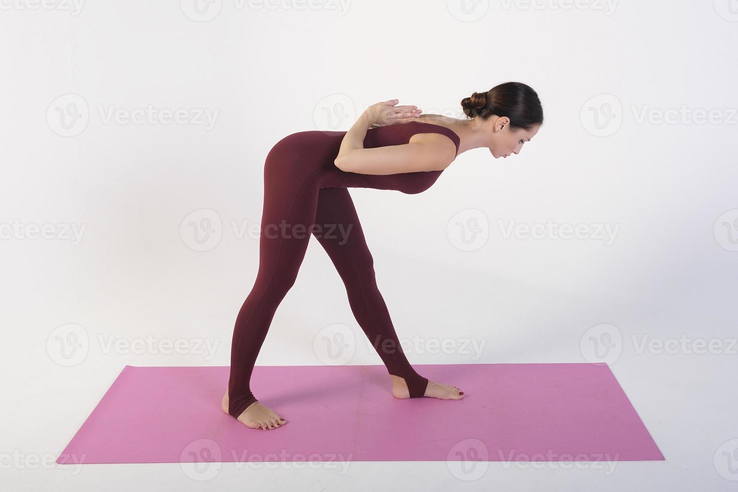 a charming girl demonstrates stretching and yoga asanas in a photo studio