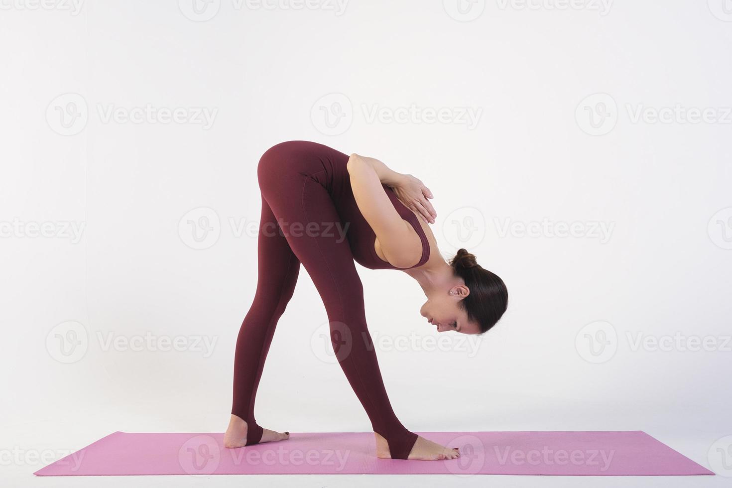 una chica encantadora demuestra estiramientos y asanas de yoga en un estudio fotográfico foto