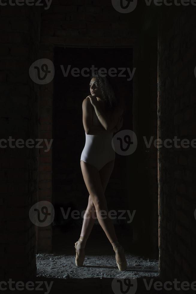 a charming ballerina in a bodysuit poses ballet elements in a headdress in a photo studio