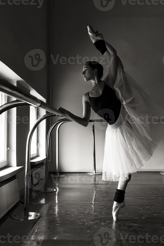 a charming ballerina in a bodysuit poses ballet elements in a headdress in a photo studio