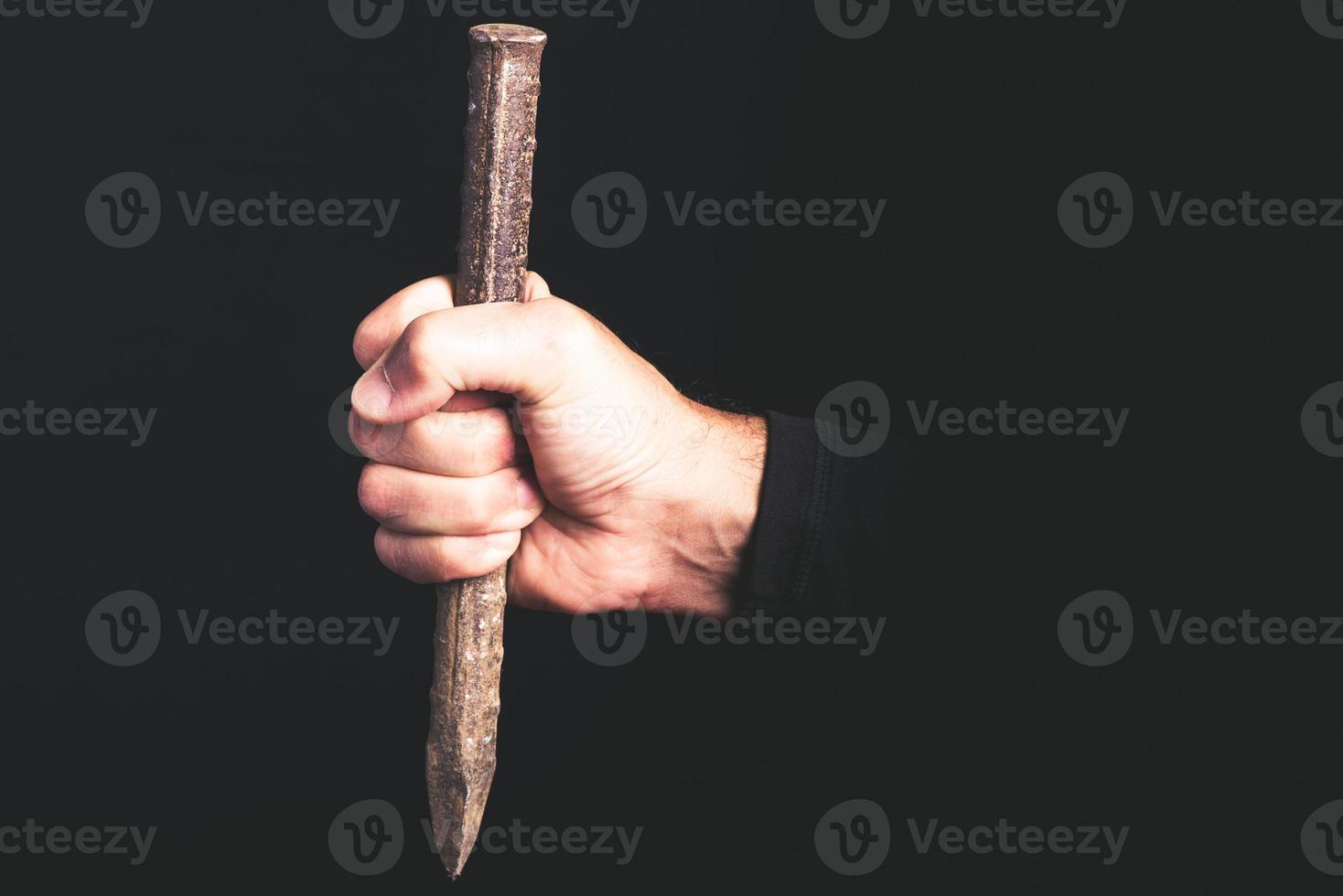 awl in a man hand on black background - maintenance sercice concept photo