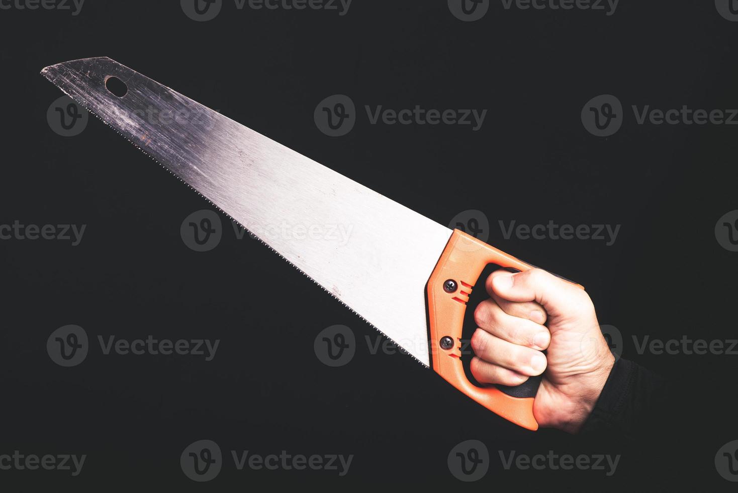 carpenter saw in a man hand on black background - maintenance sercice concept photo