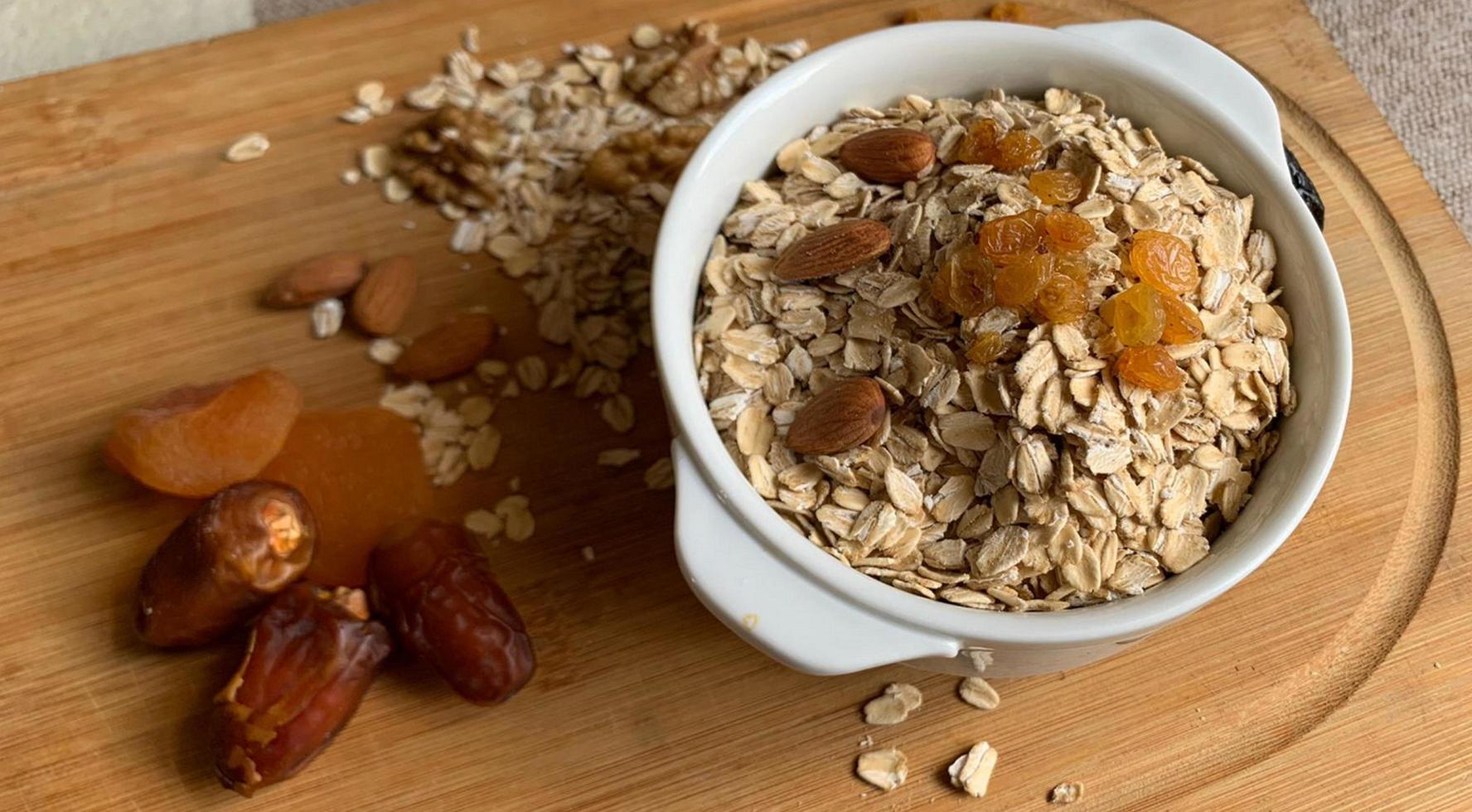 A bowl of oats with a few almonds and some dried fruits on a wooden base photo