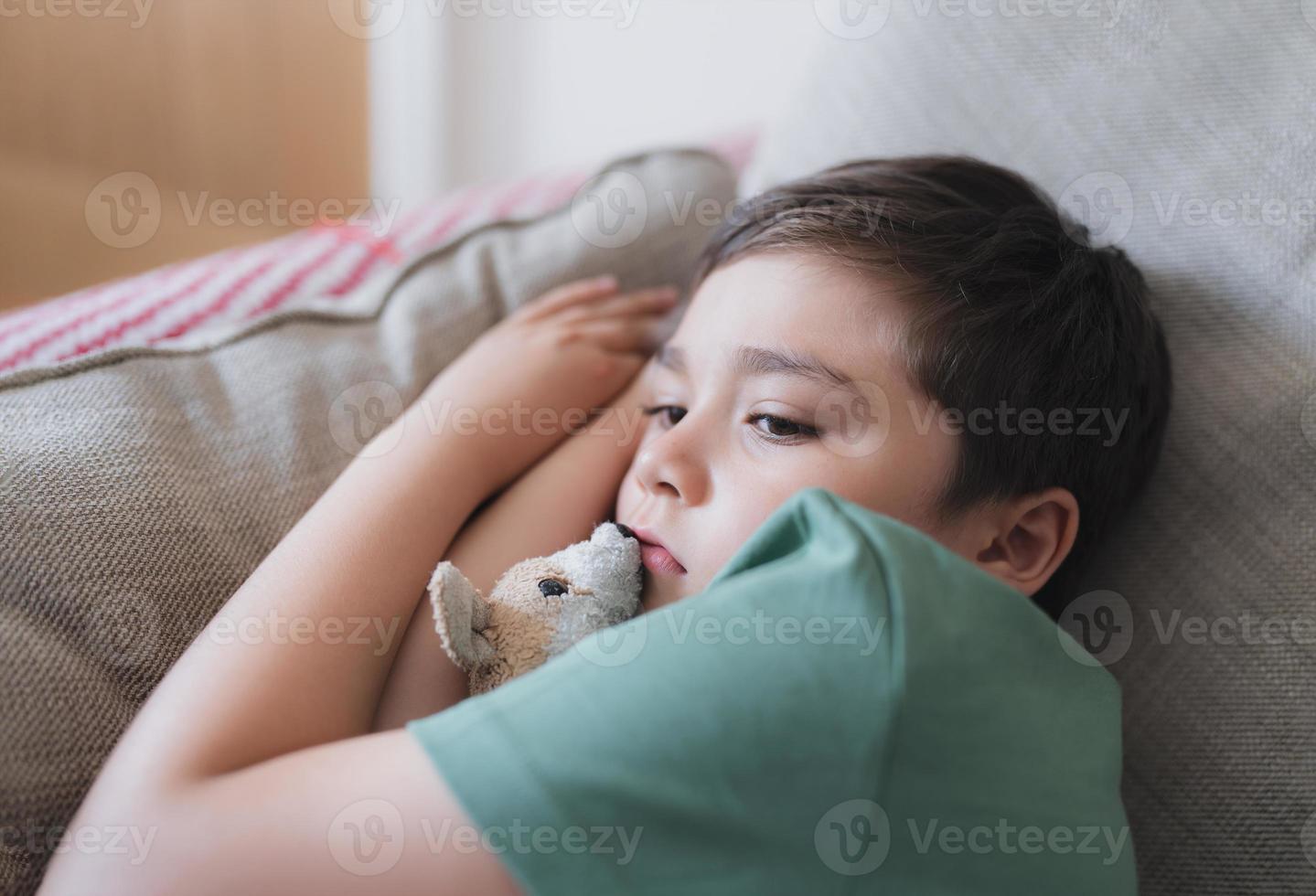 Dramatic portrait Kid bored face looking deep in thought, Lonely boy with thinking face sitting alone on sofa,Upset preschool child with unhappy or sad face,Spoiled children,Mental health photo