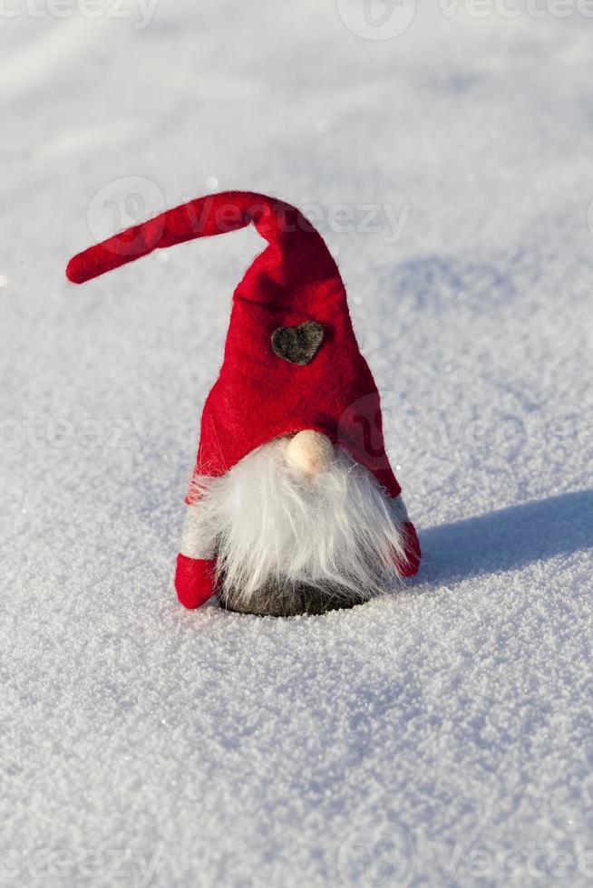 un enano con un sombrero rojo en la nieve foto