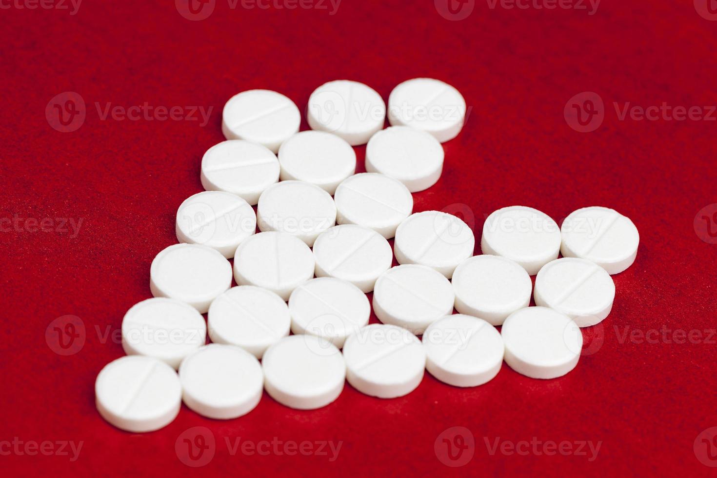 medical medicines tablets stacked on a red background in the shape of a heart photo