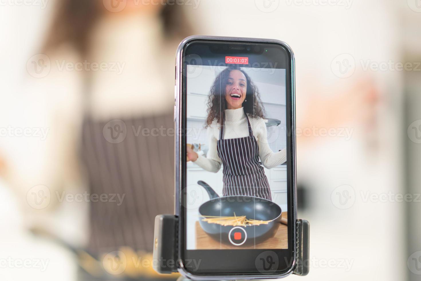 Latin woman shooting video and cooking at the kitchen photo