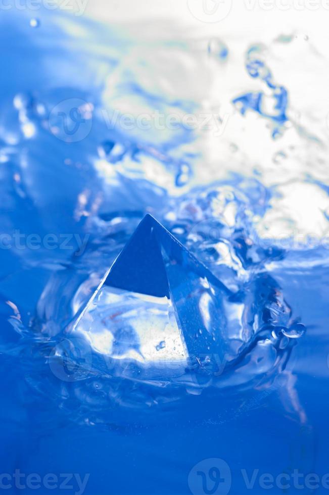 Abstract blue background with water splashen and a geometric object. Pyramid in water. photo