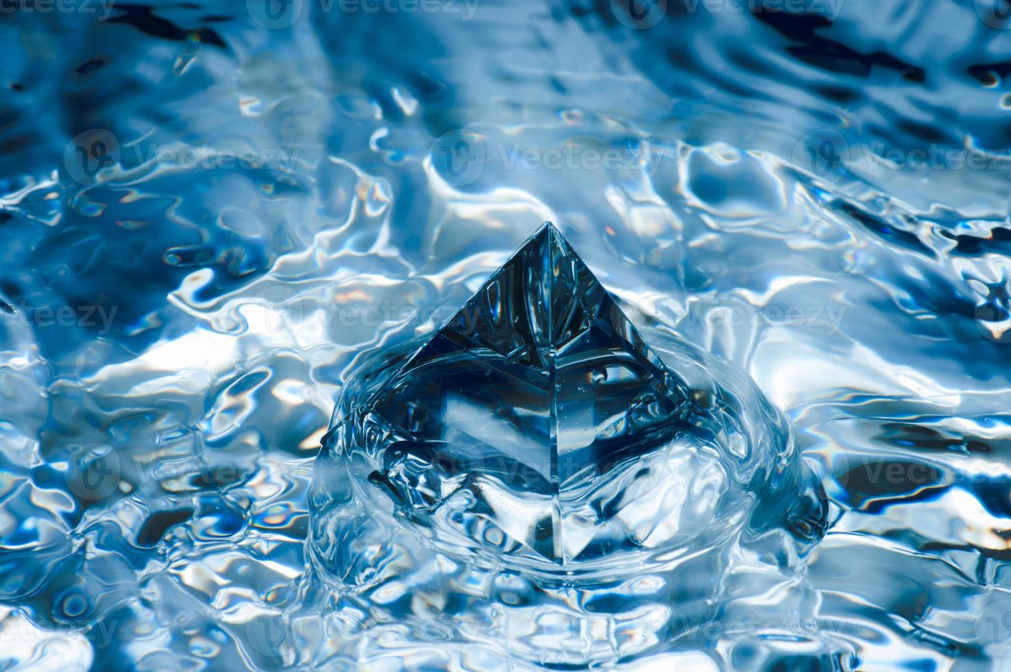 Abstract blue background with water splashen and a geometric object. Pyramid in water. photo