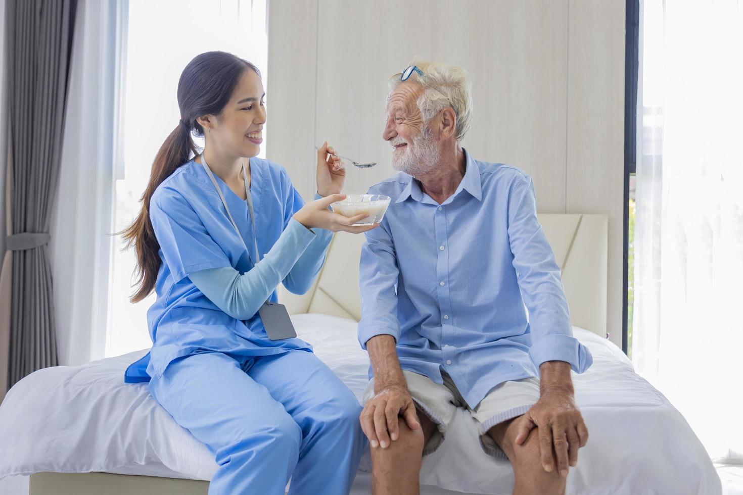 Hospice nurse is feeding porridge food to Caucasian man at pension retirement center for home care rehabilitation and post treatment recovery process photo