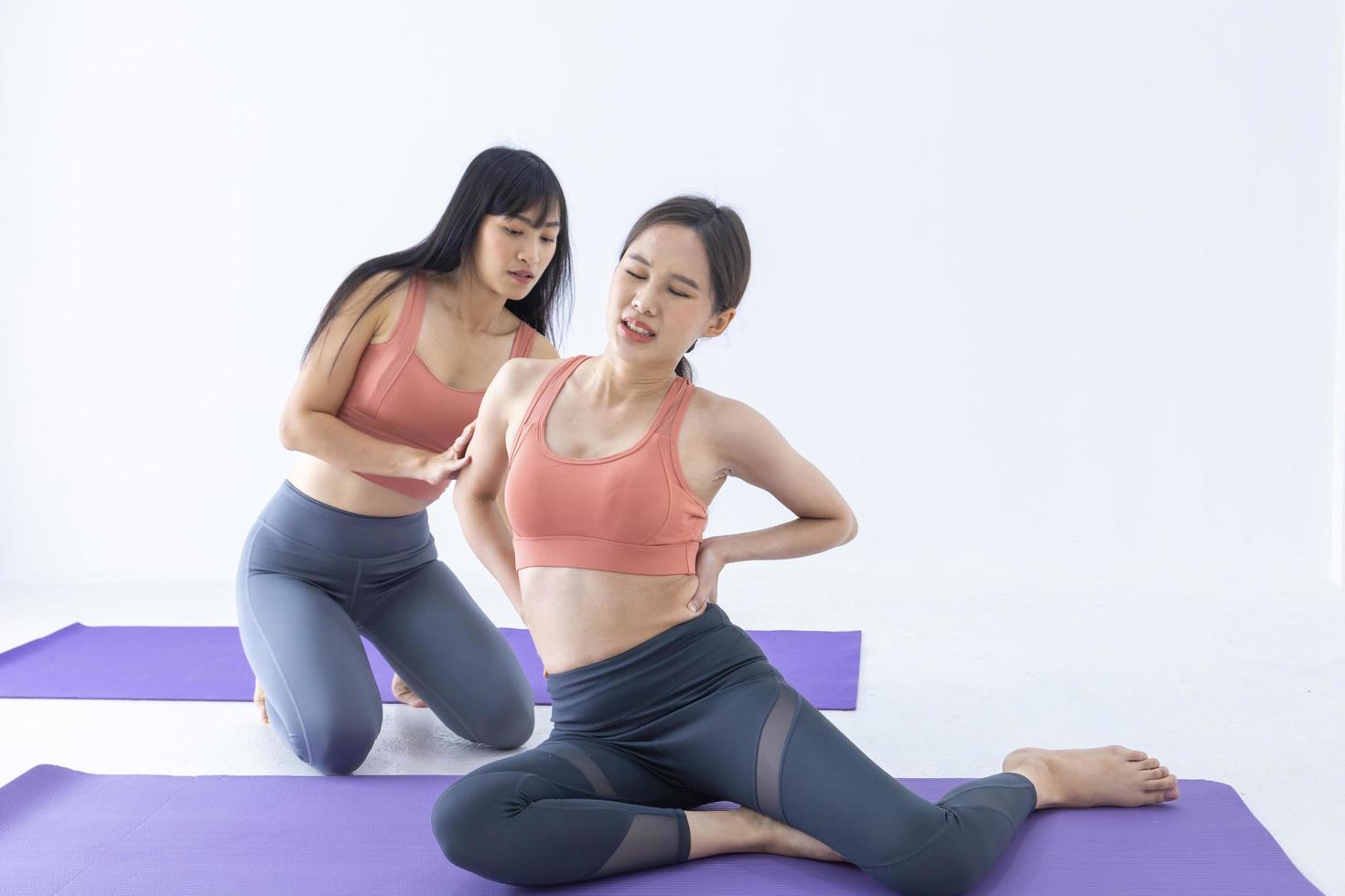 Asian woman got injury after over stretching exercise in yoga class with her trainer helping to support photo