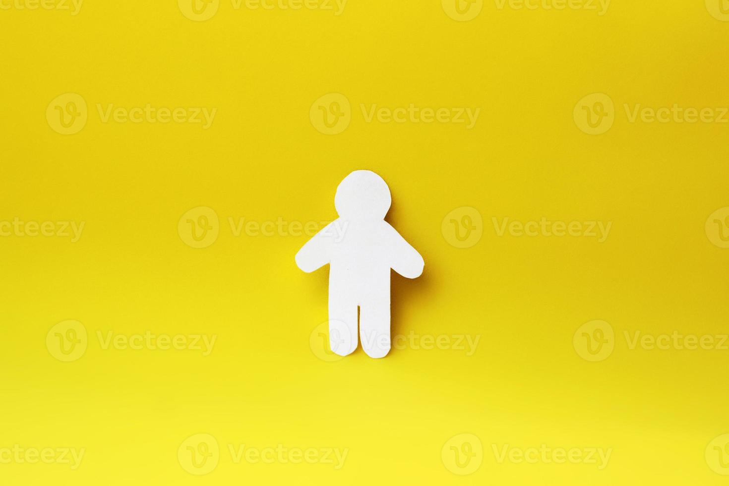 Silhouette of a man of white paper, cut by hand. In the center of the photo on yellow background