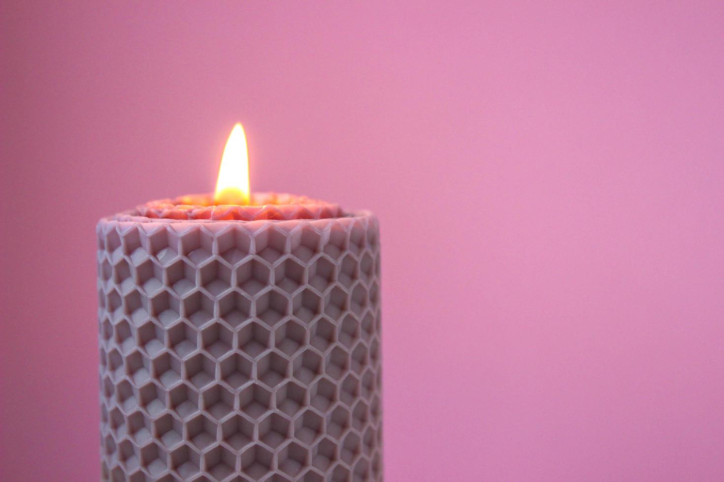 burning wax candle on pink background photo