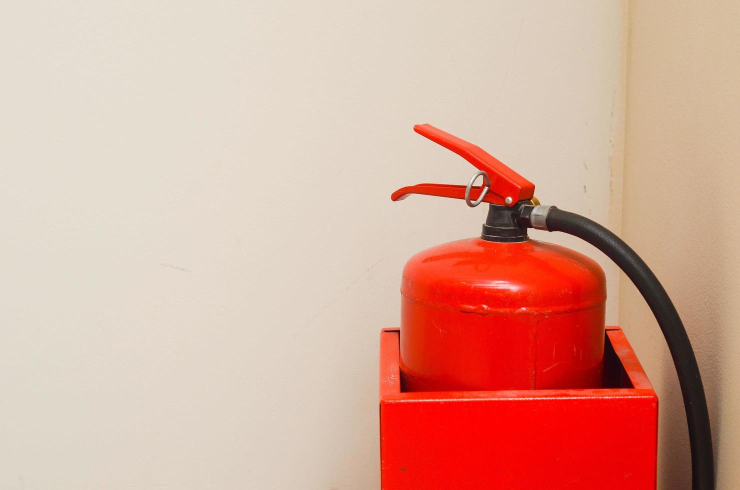 Red fire extinguisher in a metal container in the corner of a white wall.Safety. photo