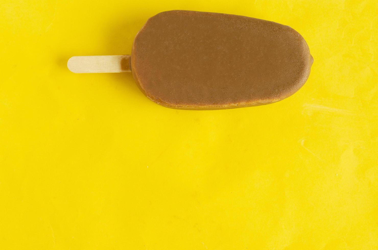 Banana vanilla popsicle in chocolated glaze on bright yellow background,copyspace. photo