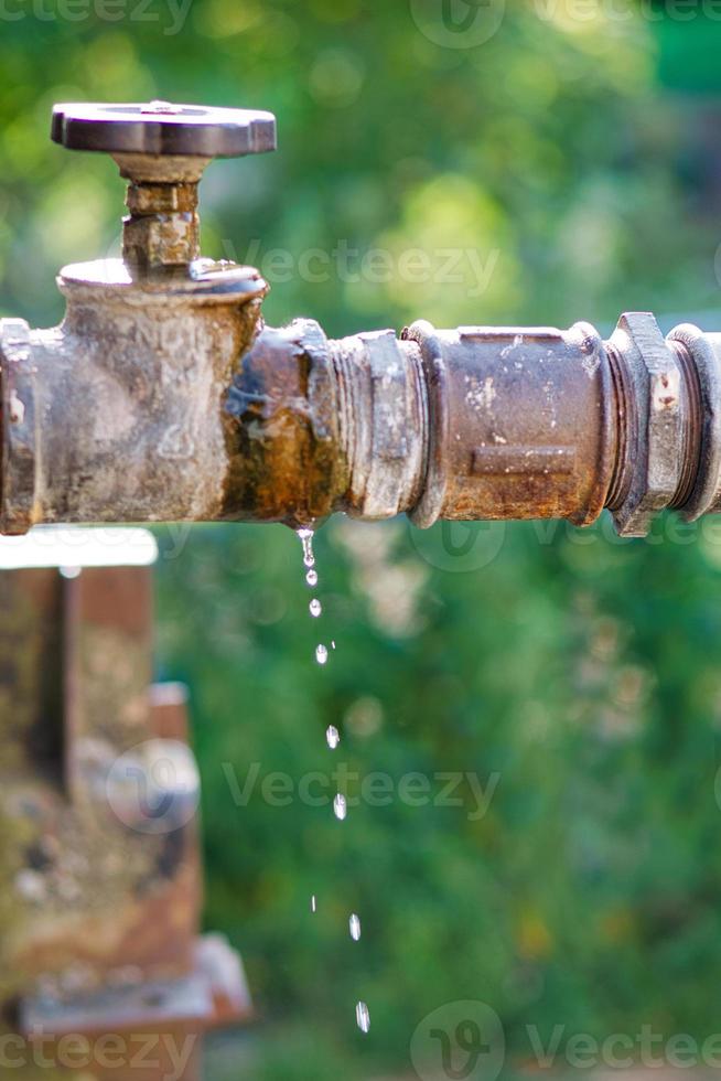 grifo que gotea de un tanque de agua al aire libre. gotas caen de la tubería foto