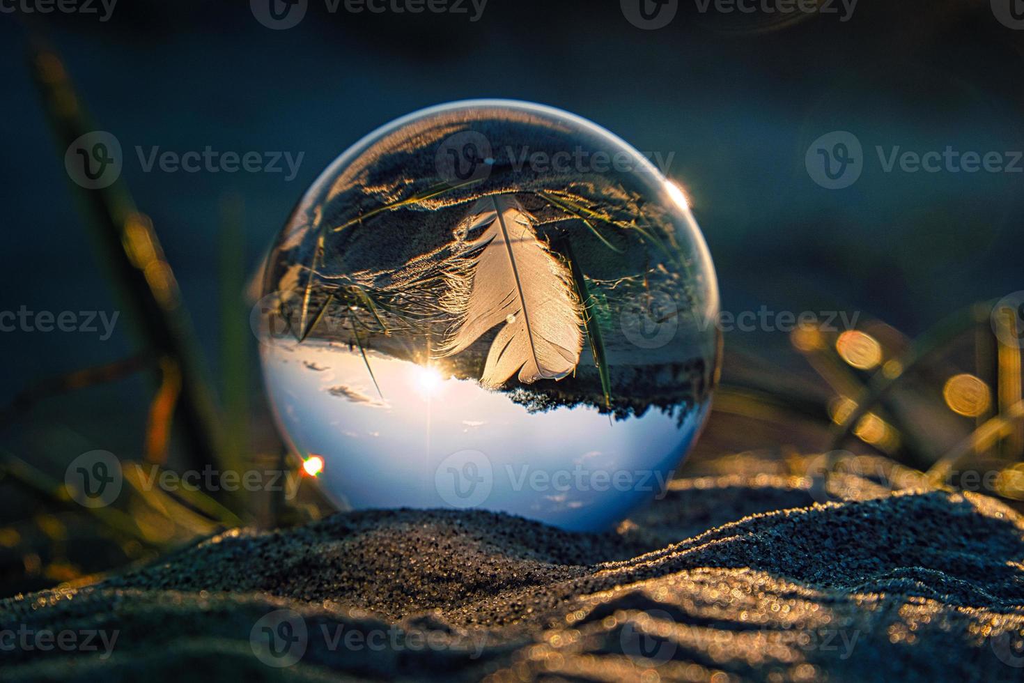 bola de cristal en la playa del mar báltico en zingst con una pluma representada en la bola con el paisaje. foto