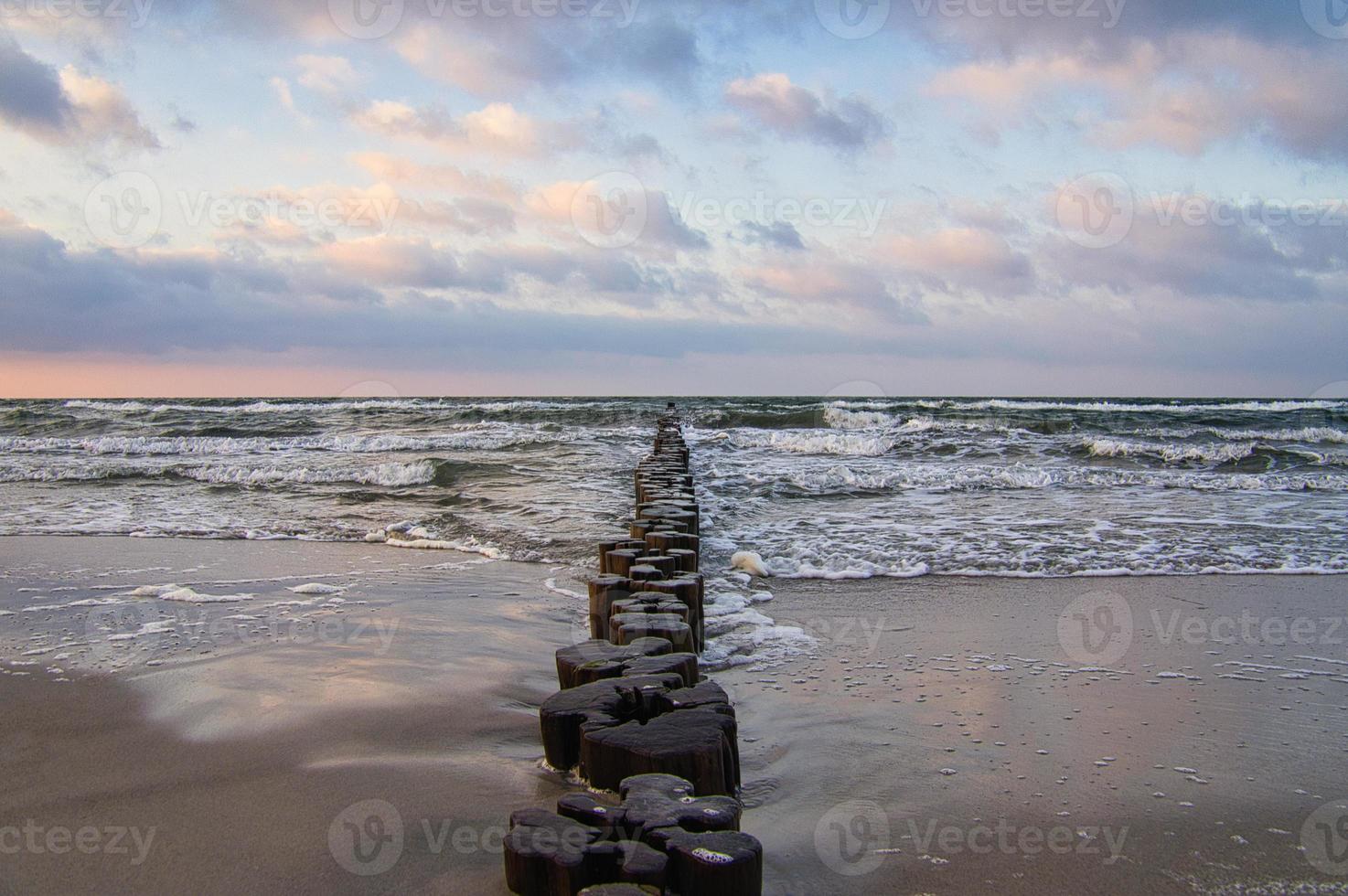 espigones en la playa del mar báltico en zingst. las olas rompen en la madera foto