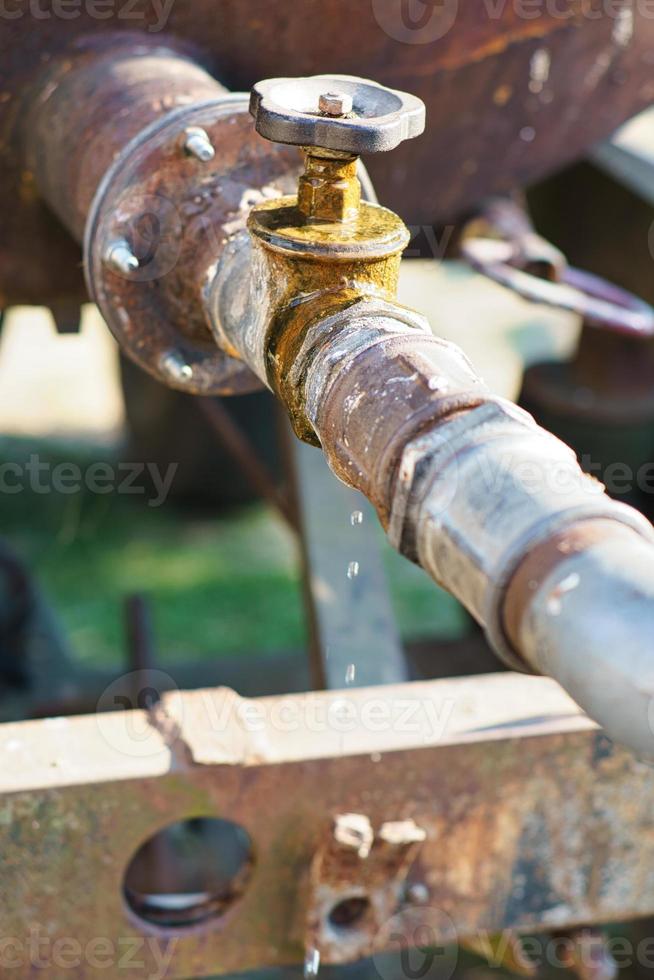 grifo que gotea de un tanque de agua al aire libre. gotas caen de la tubería foto