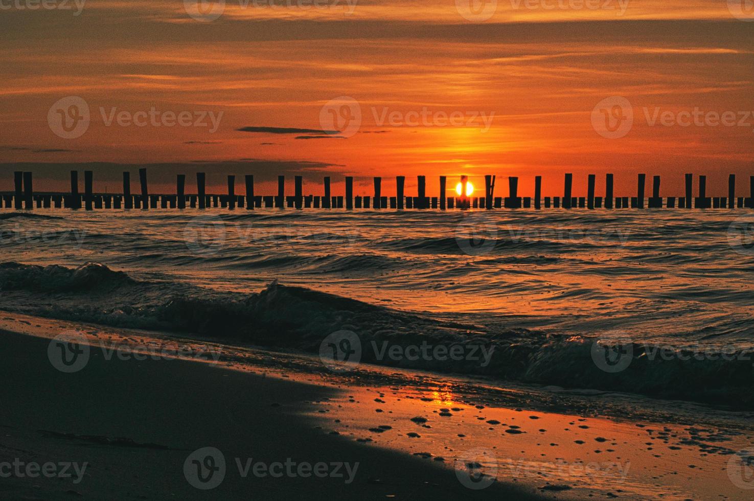 sunset in Zingst at the sea. red orange sun sets on the horizon. Seagulls circle in the sky photo