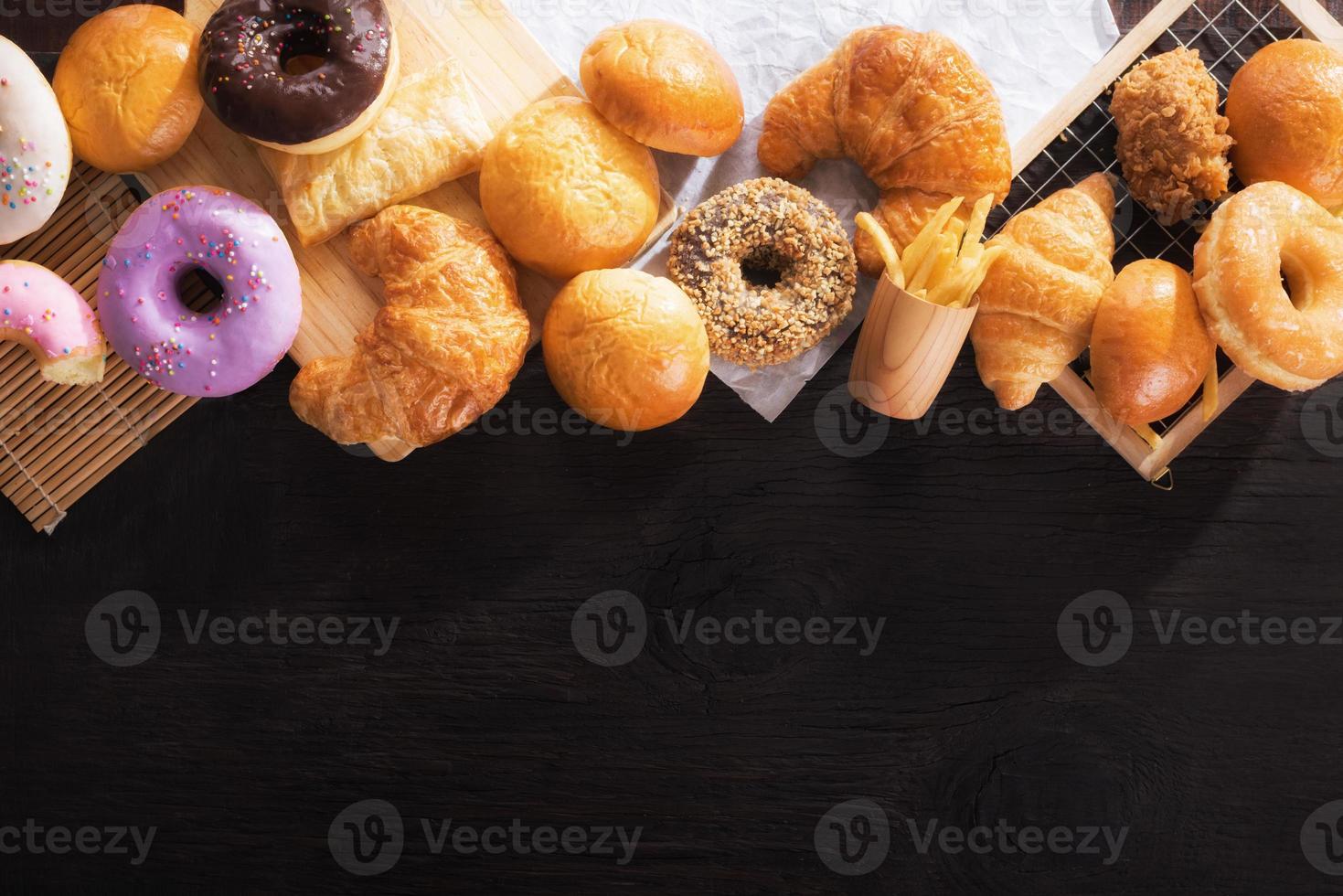 assorted junk food multiple type on black wooden table of top view with copy space. photo