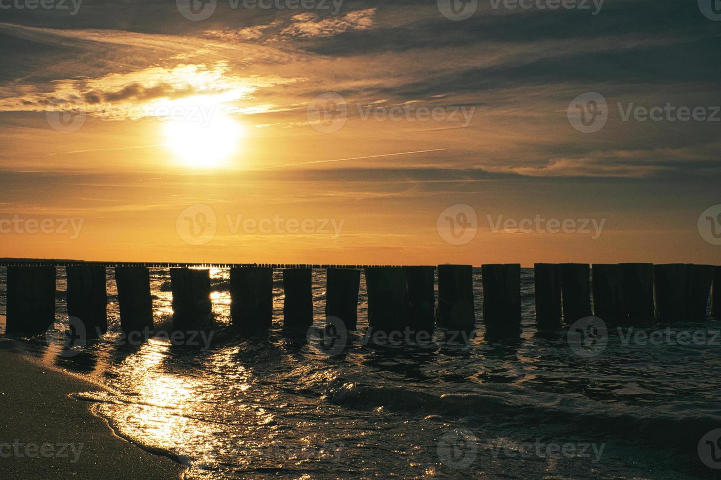 puesta de sol en zingst en el mar. el sol rojo anaranjado se pone en el horizonte. círculo de gaviotas en el cielo foto