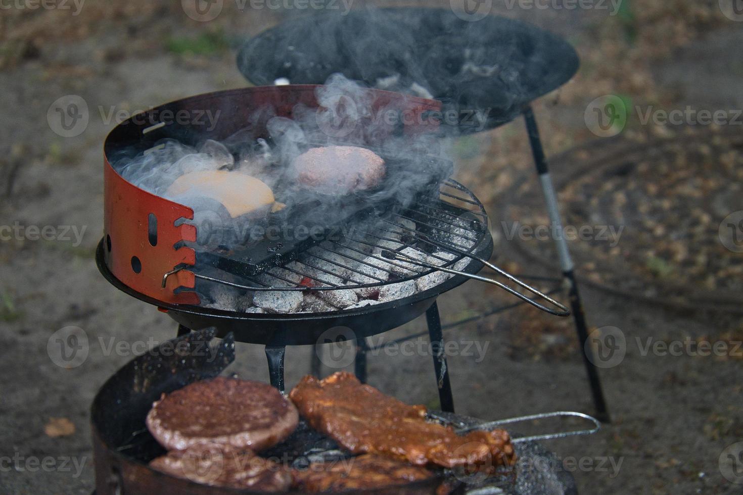 Grill with coal, grate and meat. Burger with cheese in the preparation on the grill photo