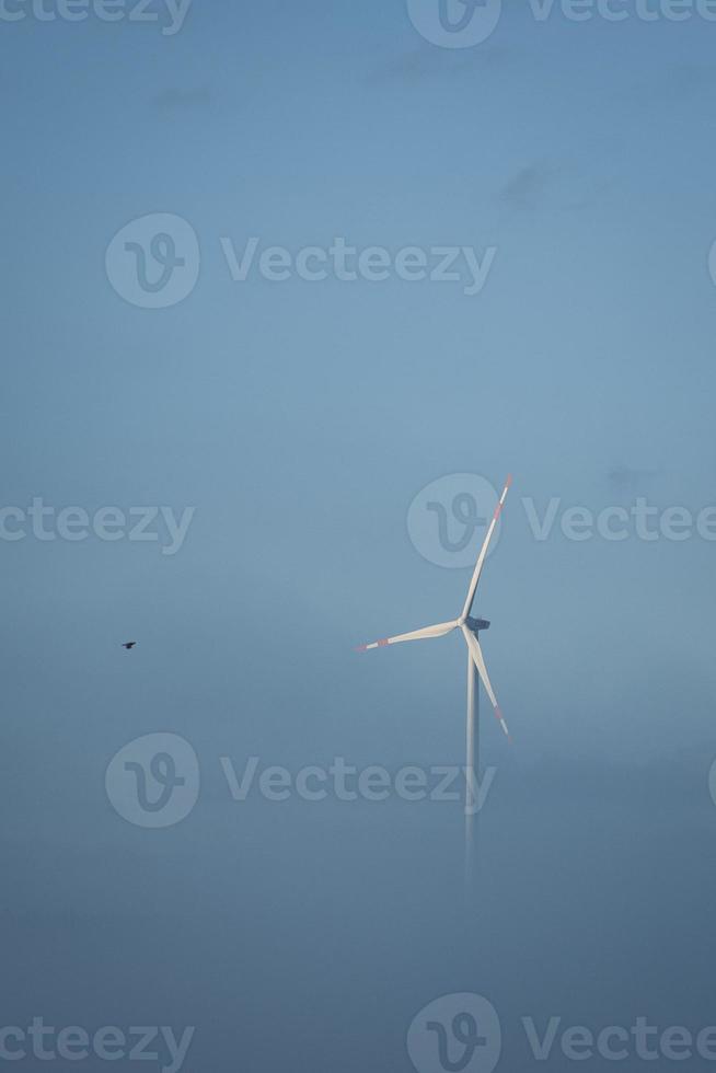 molino de viento en un paisaje brumoso. energía renovable para un futuro con conciencia ambiental foto
